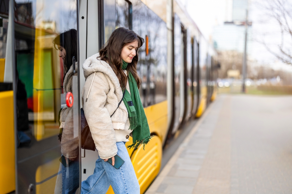 Young,Woman,Getting,Off,The,Tram,At,A,Stop,In